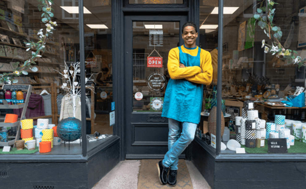 A small business owner standing in front of their store.