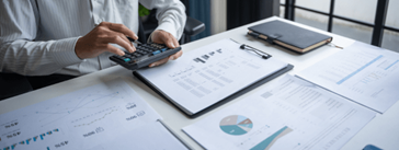 Someone sitting at a desk typing on a calculator.