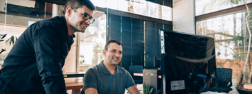 Two people looking at a computer on a desk.