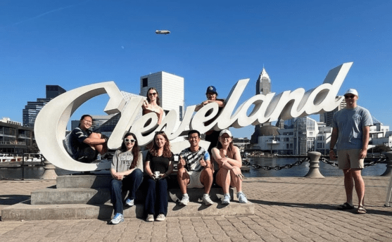 A group of interns posing with a "Cleveland" sign in front of the city.
