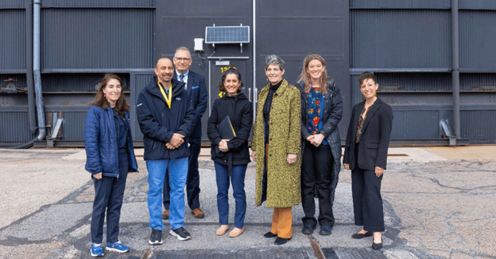 Group of people standing together in front of industrial doors.