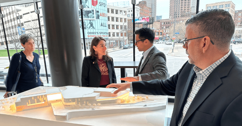 A group of people talk in front of an architectural model.