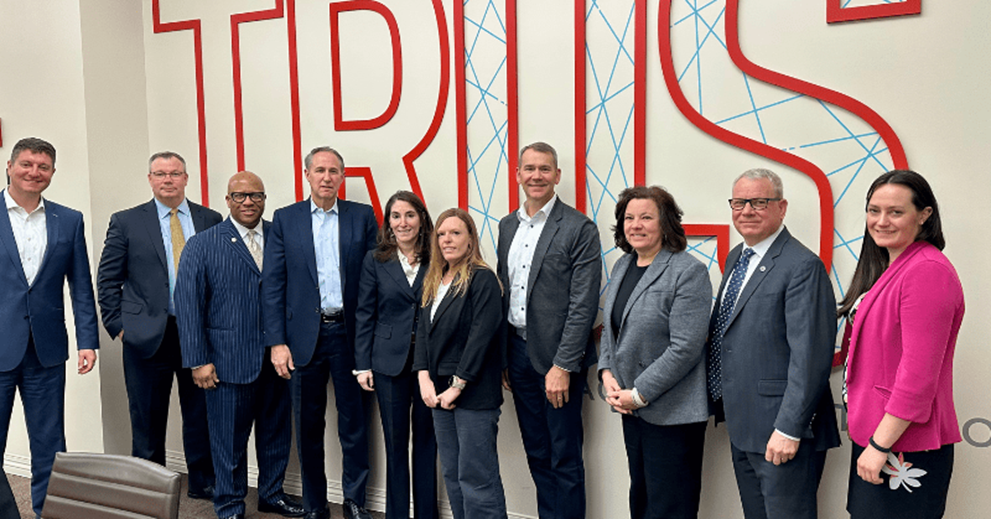 A group of people stand in front of a wall that says “trust”