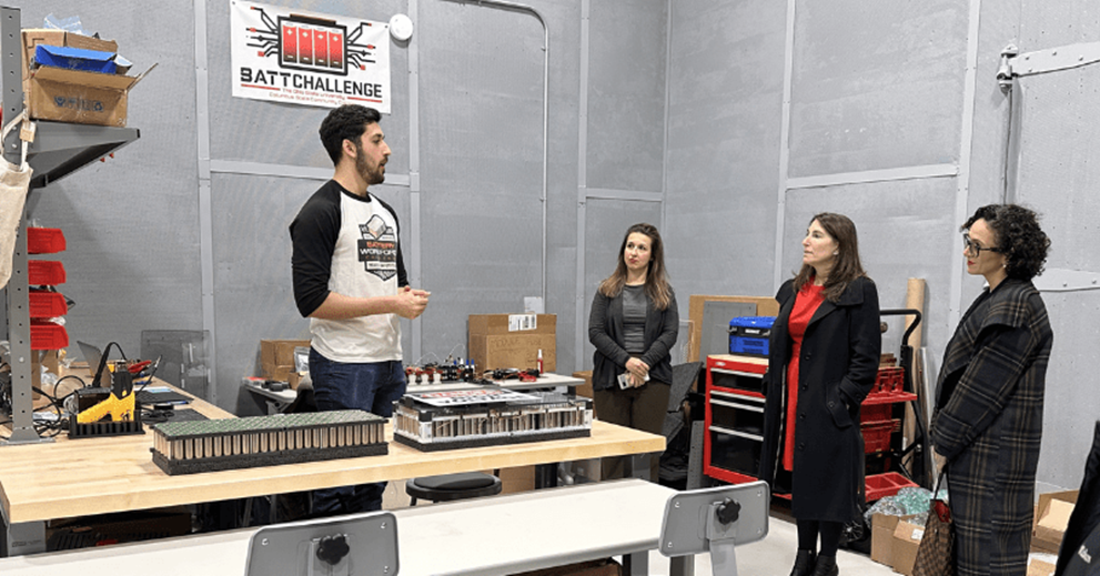 Group of people look at a project in factory setting.