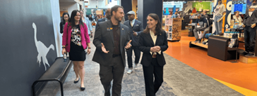 A group of people walking down a hallway with a gift store to the right.