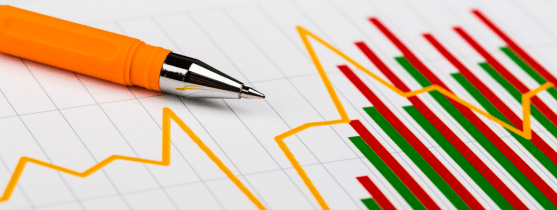 A pen resting on top of a paper depicting a bar chart and line graph.