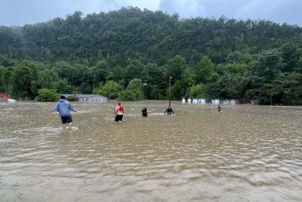 Residents of Letcher County, Kentucky, use a rope line to help a family leave their flooded home.