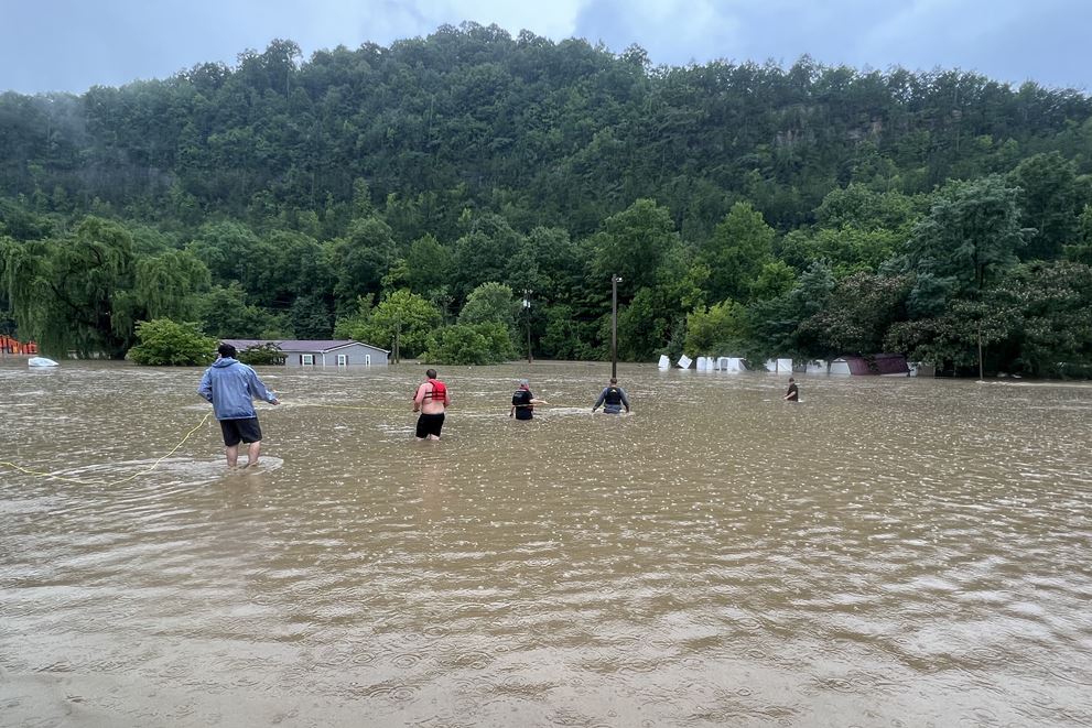 Residents of Letcher County, Kentucky, use a rope line to help a family leave their flooded home.