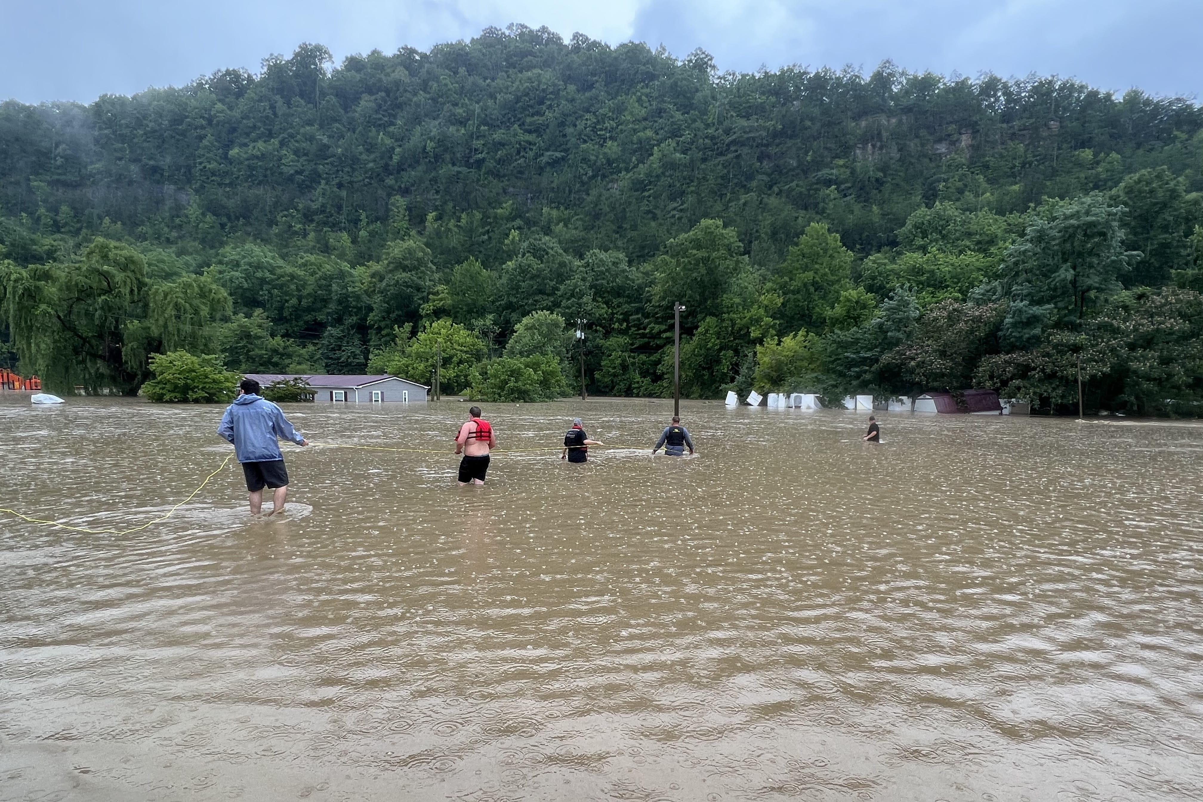 Residents of Letcher County, Kentucky, use a rope line to help a family leave their flooded home.