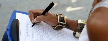 Someone filling out a survey on a clipboard.