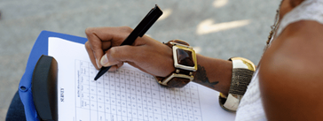 Someone filling out a survey on a clipboard.