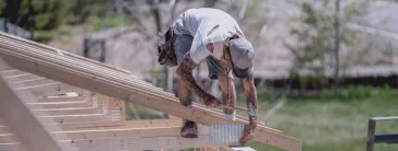 A construction worker building a frame for a roof.