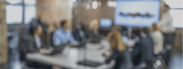 Soft focus image of a conference room full of people.